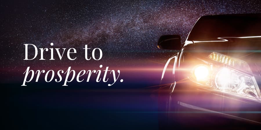 An up-close view of the headlights of a sports car against a night sky. To the left, the words: drive to prosperity.