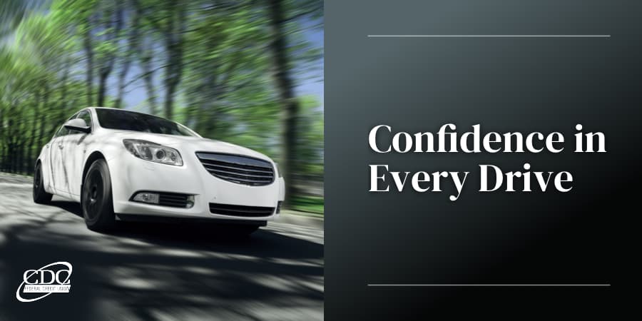A white sedan driving down a road lined with trees. To the right, the words: confidence in every drive.