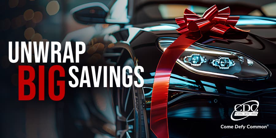 A close up of a black luxury vehicle with a red bow. To the left, the words: unwrap big savings.