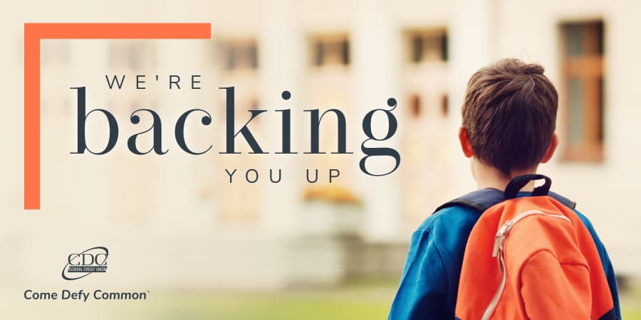 A young boy wearing a bright, orange back pack. To the left, the words: we're backing you up.
