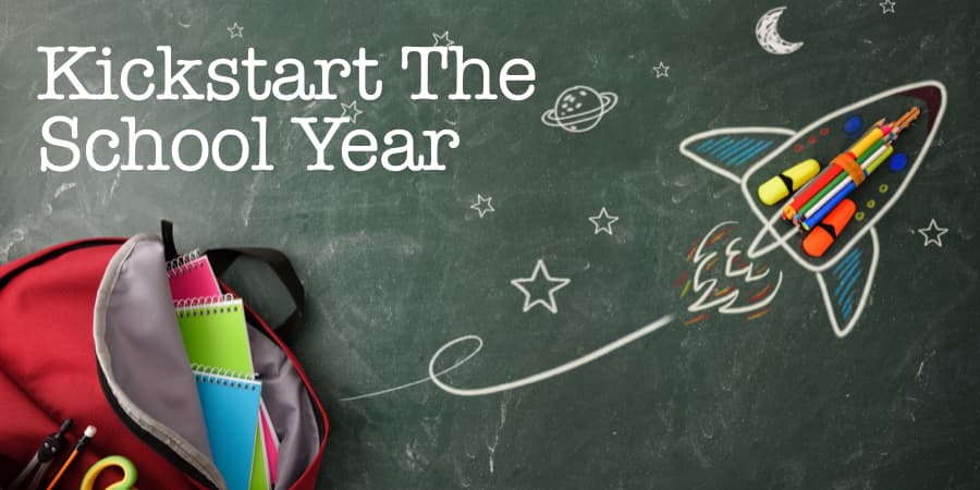 Young student bookbag filled with school supplies and a hand drawn rocketship resting on chalk board. At the left, the words: kickstart the school year.