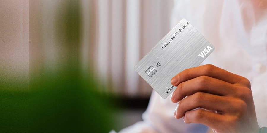 A hand holding the CDC FCU Visa Platinum credit card.