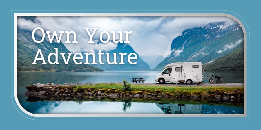 A window view showing an RV parked on the shoreline of a beautiful lake in between mountains. At the top left, the words: own your adventure.