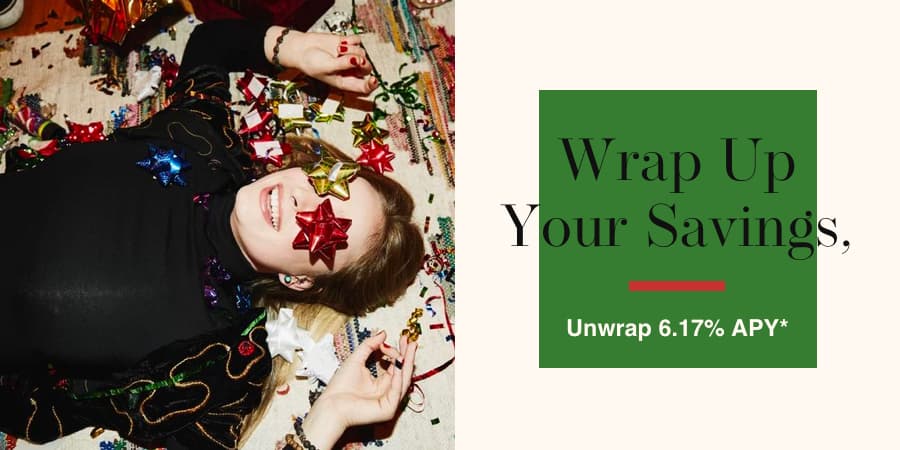 A young woman laying down surrounded by holiday items. To the right, a green box on top of a white box with the words wrap up your savings unwrap 6.17% APY*.