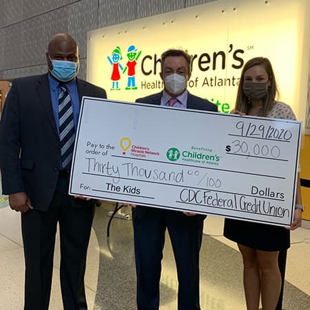 Two CDC FCU employees presenting a human-sized checked to the Children's Miracle Network.