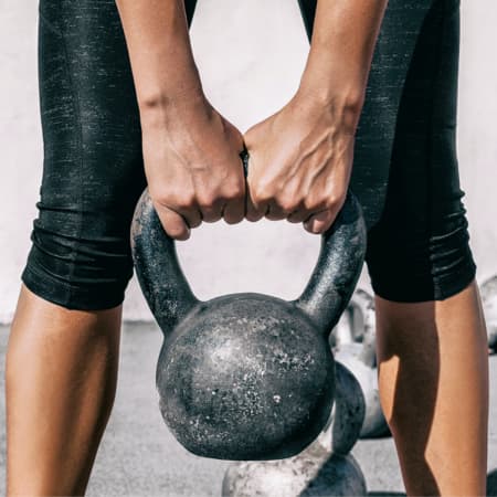 A woman excercising with a kettlebell.