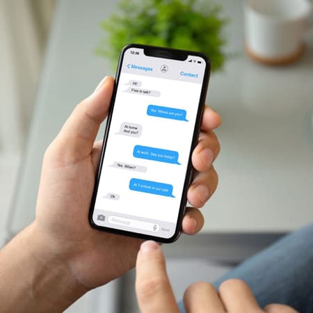 A man holding a smart phone with the text message app open.