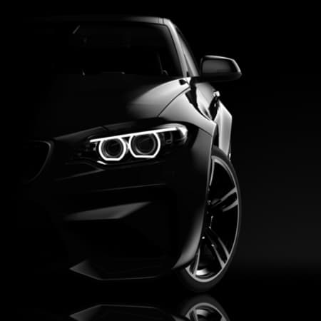 Front view of a luxury sports car with LED headlights in focus against a dark background.