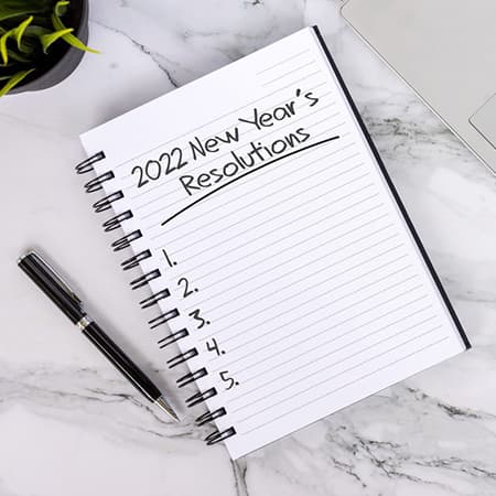 A notebook open to a page with the following words: 2022 new year's resolutions.
