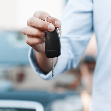 A man holding a set of keys for a new car.