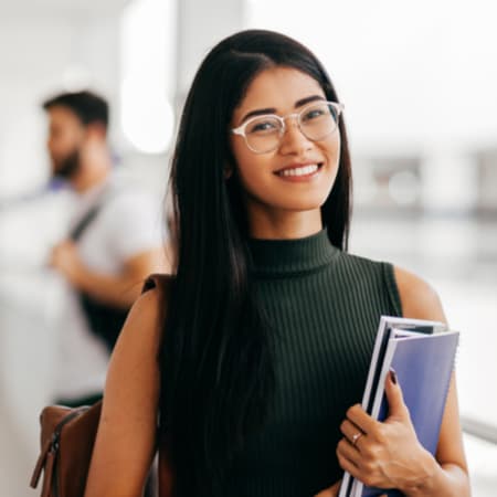 A happy young adult student female student holding books.