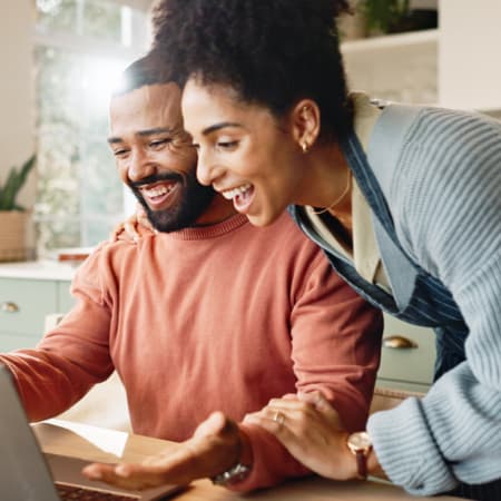 A happy African American couple looking at a laptop screen.