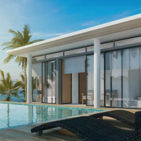 A view of a modern deck and pool looking into a beautiful beach home.