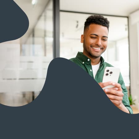 A clipping mask of a smiling young man looking at his mobile device within the shape of a puzzle piece.