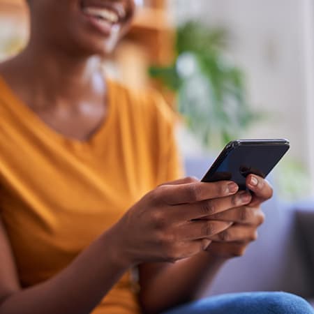 A smiling African American woman looking at her mobile device.