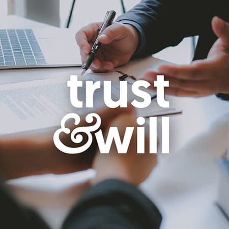 Two people signing documents. The words in the middle: trust & will.