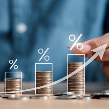 A male hand stacking up coins from smallest column to largest column to illustrate an increase.