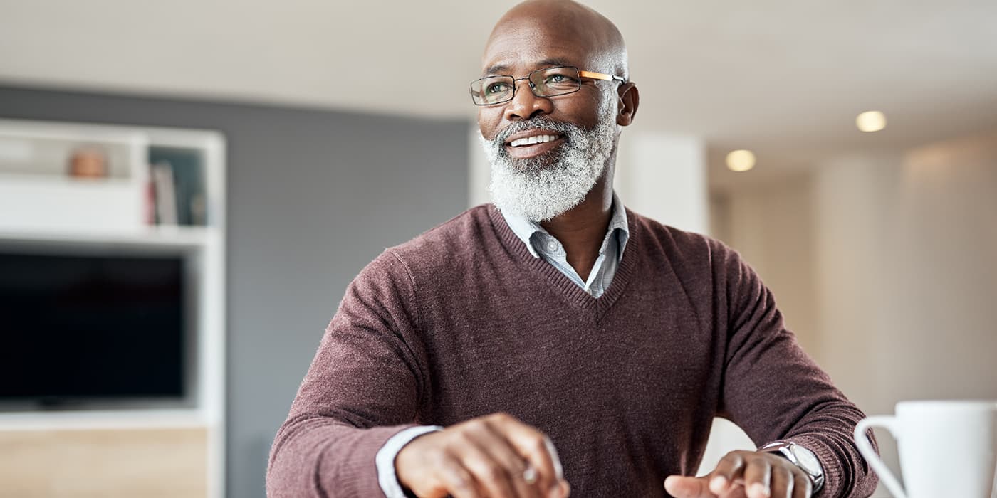 An elderly man sitting at a table drinking coffee.