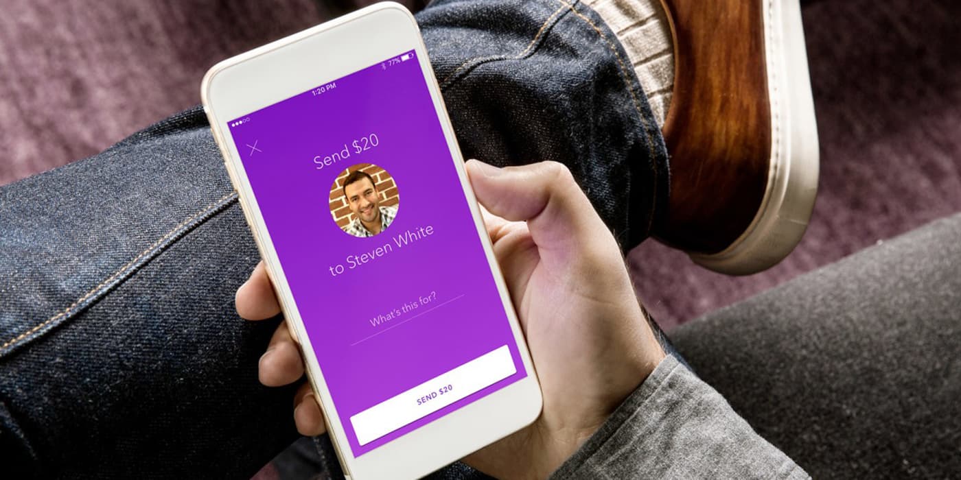 Top view of a man sitting on a couch with the zelle® mobile app open.