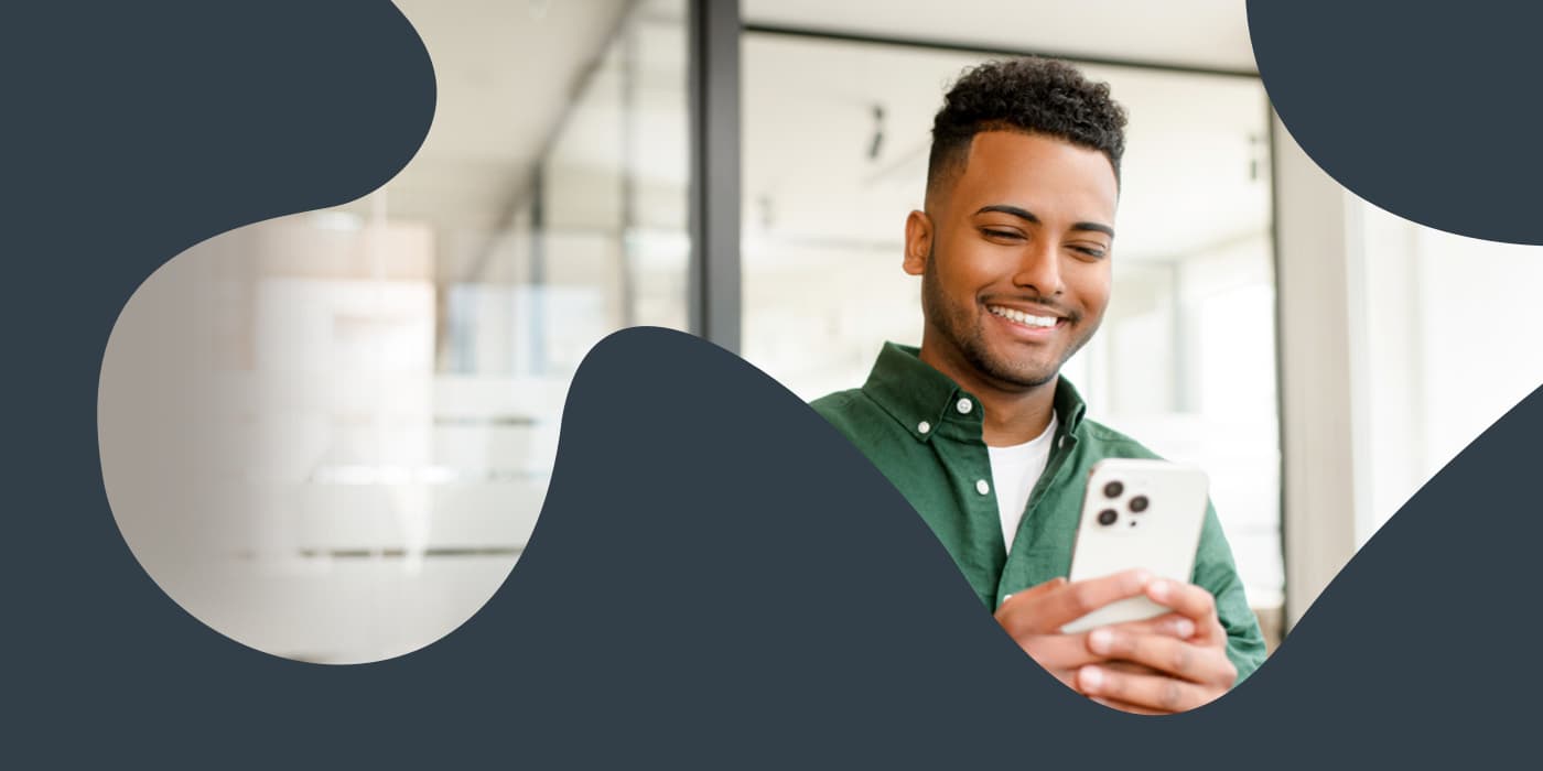 A clipping mask of a smiling young man looking at his mobile device within the shape of a puzzle piece.