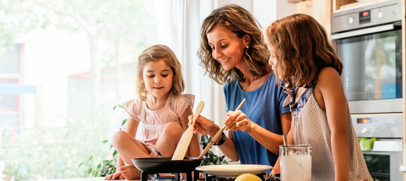 A mother and her daughters cooking on the kitchen counter.