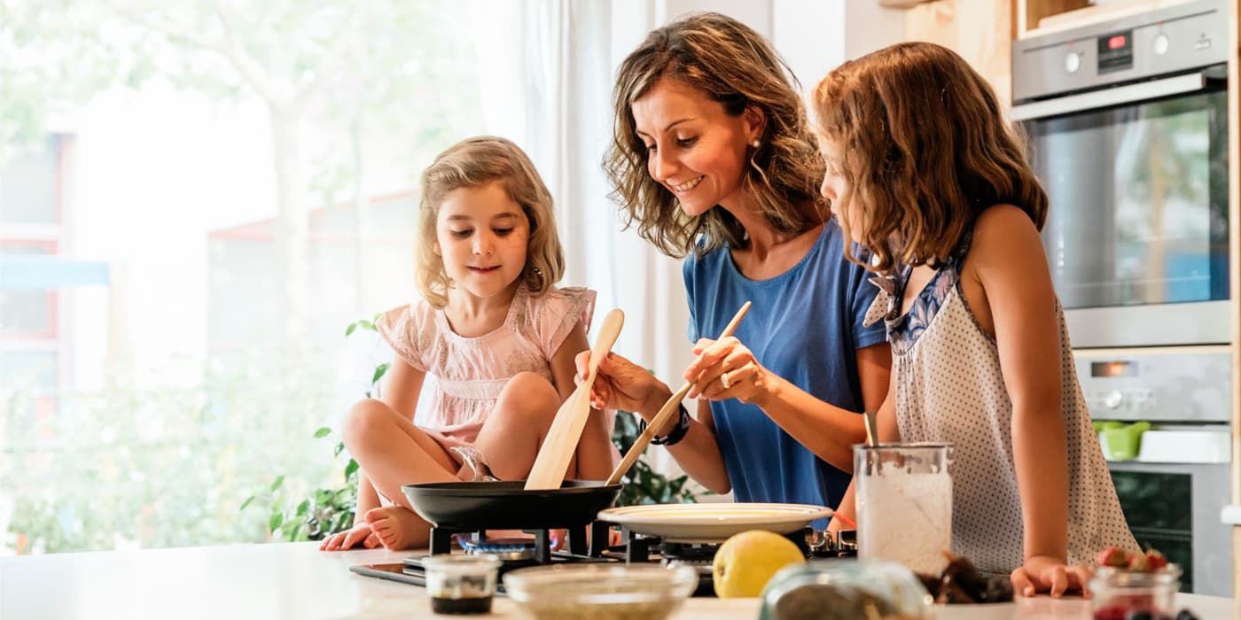 A mother and her daughters cooking on the kitchen counter.