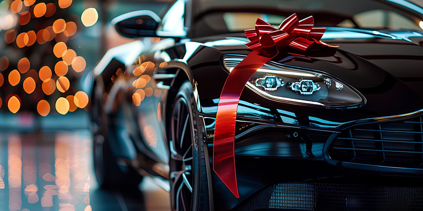 A close up of a black luxury vehicle with a red bow on the hood.