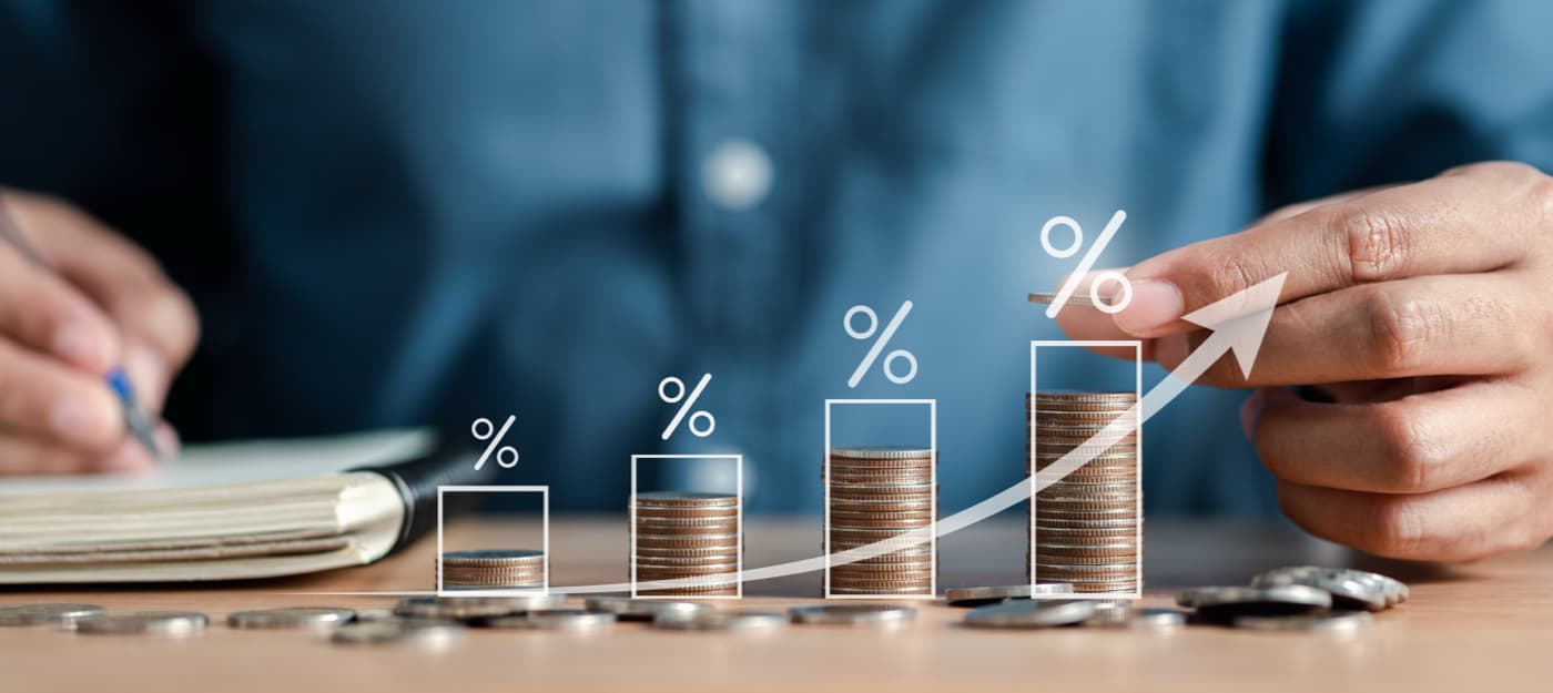 A male hand stacking up coins from smallest column to largest column to illustrate an increase.