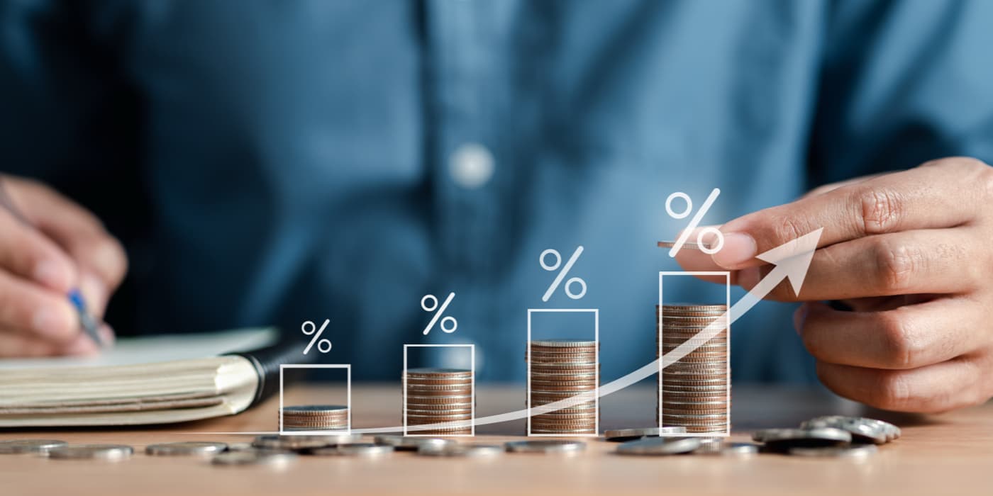 A male hand stacking up coins from smallest column to largest column to illustrate an increase.