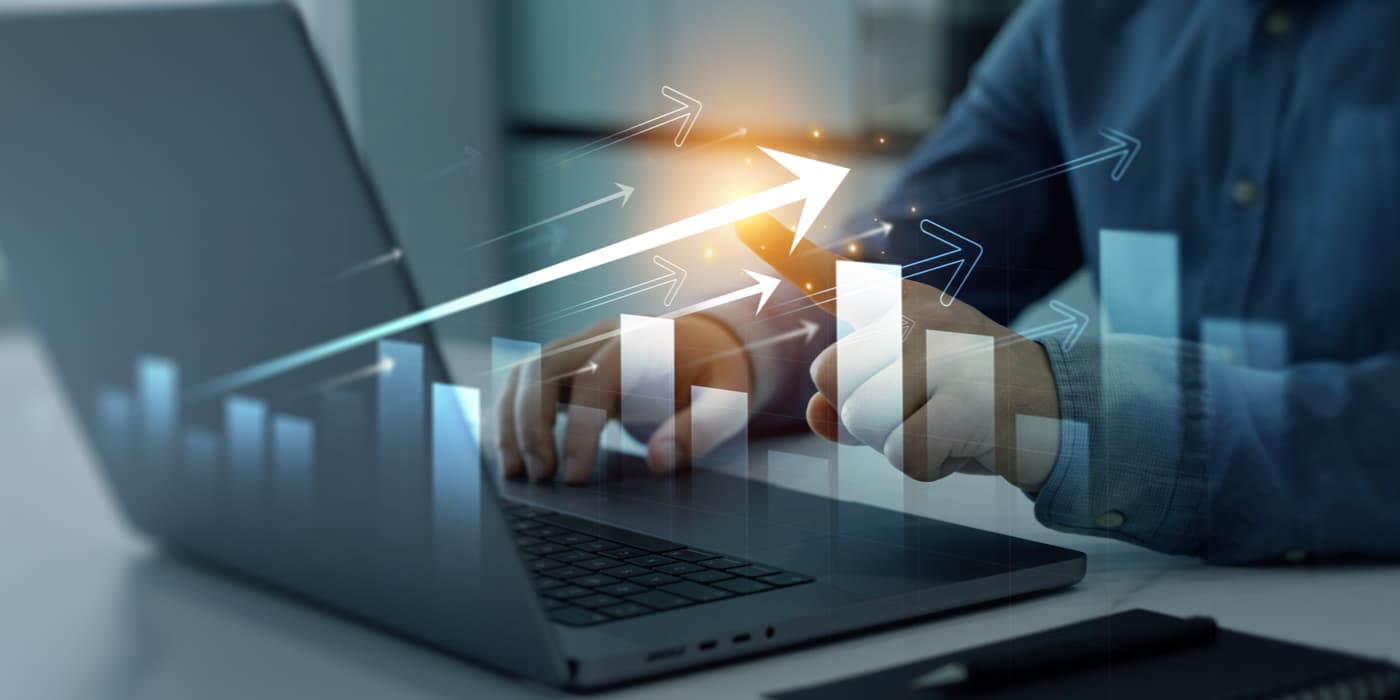 Person using a laptop with upward-trending charts and arrows overlayed on the screen, representing financial growth and increasing savings.