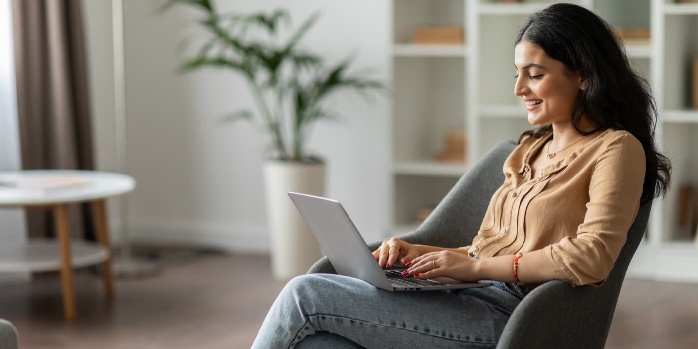 Woman seated in a chair using a laptop at home.