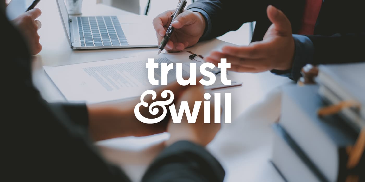 Two people signing documents. The words in the middle: trust & will.