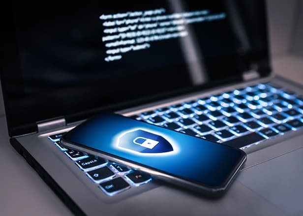 A smart phone resting on a laptop showing a padlock on the homescreen.