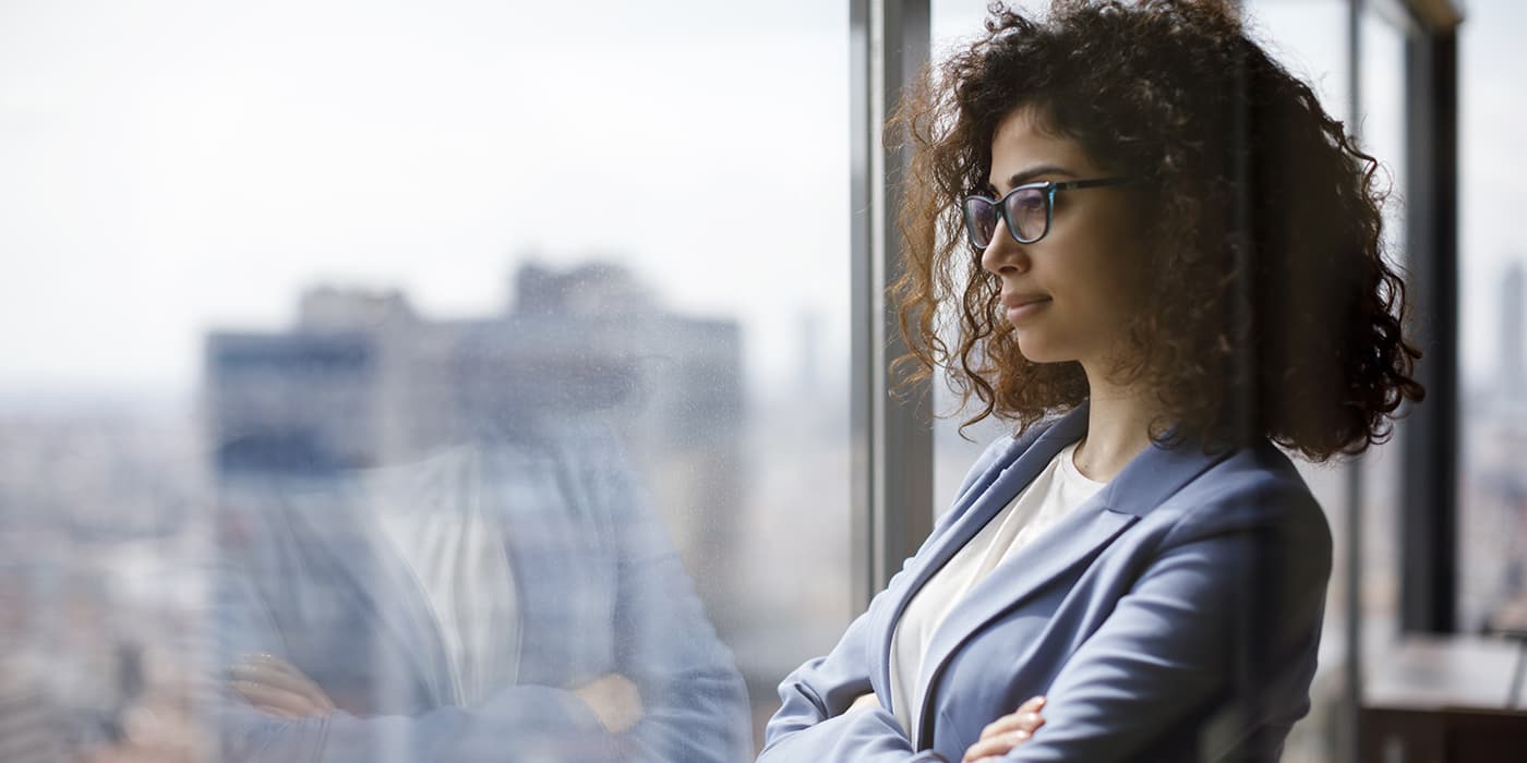 A professional woman looking out an office window.